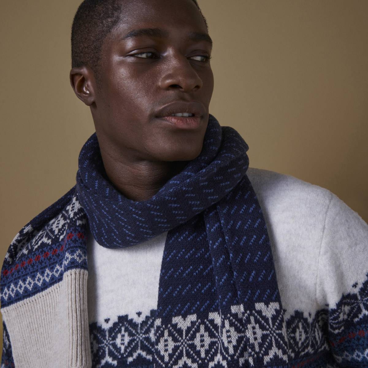 Man wearing knitted jumper and scarf. Shop knitwear